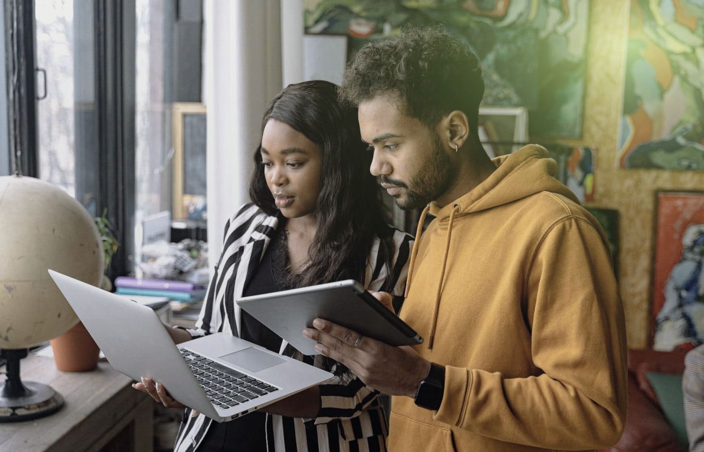 Two colleagues reviewing work together on a tablet and laptop